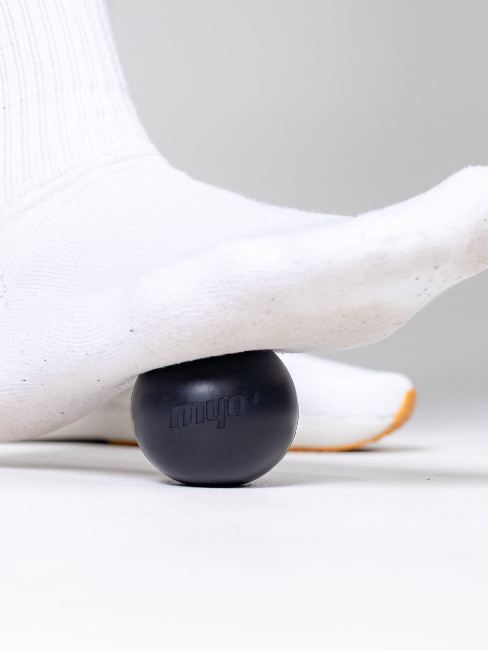 Athlete using Myo+ massage ball for foot arch trigger point release